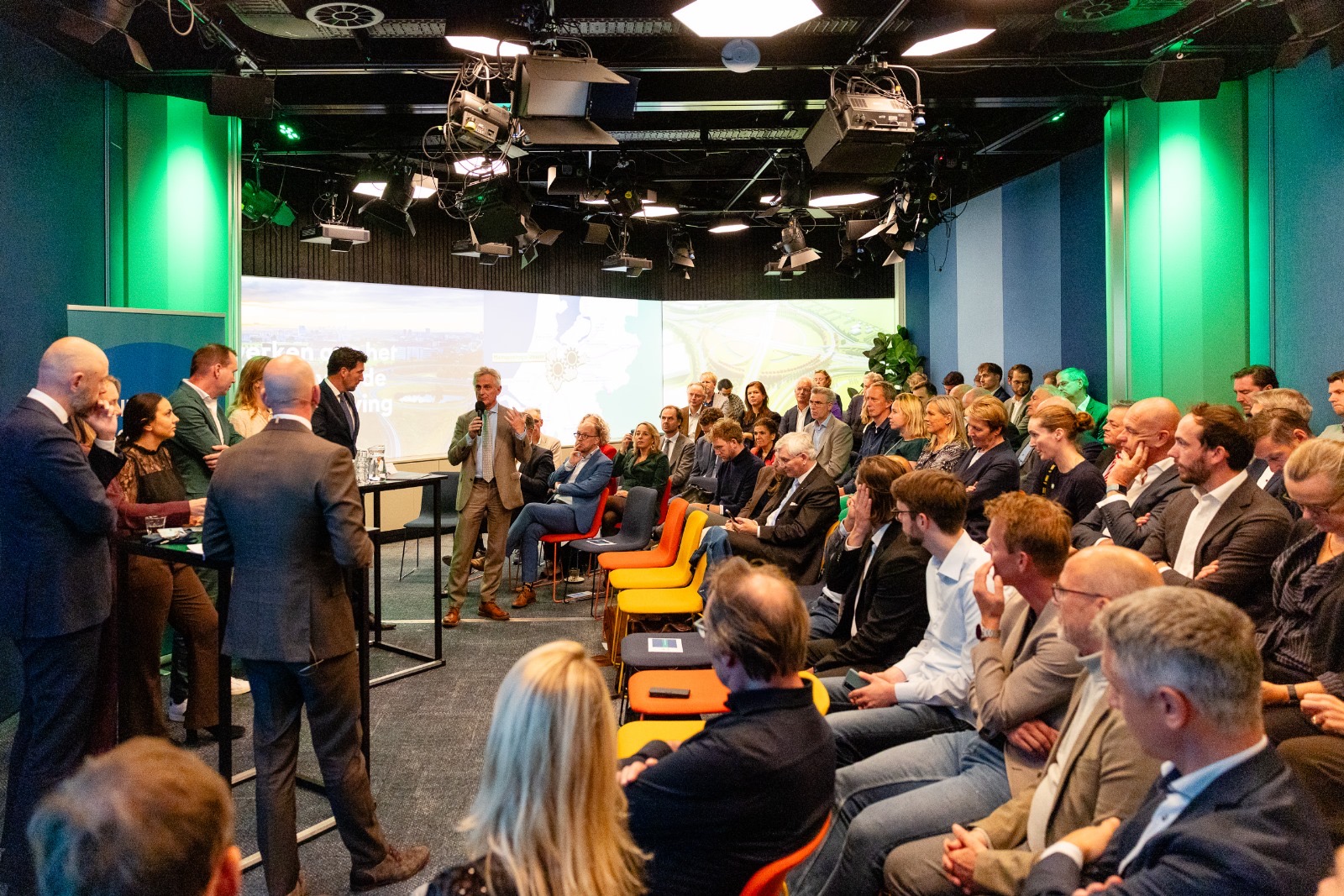 Grote groep toehoorders luistert naar paneldiscussie